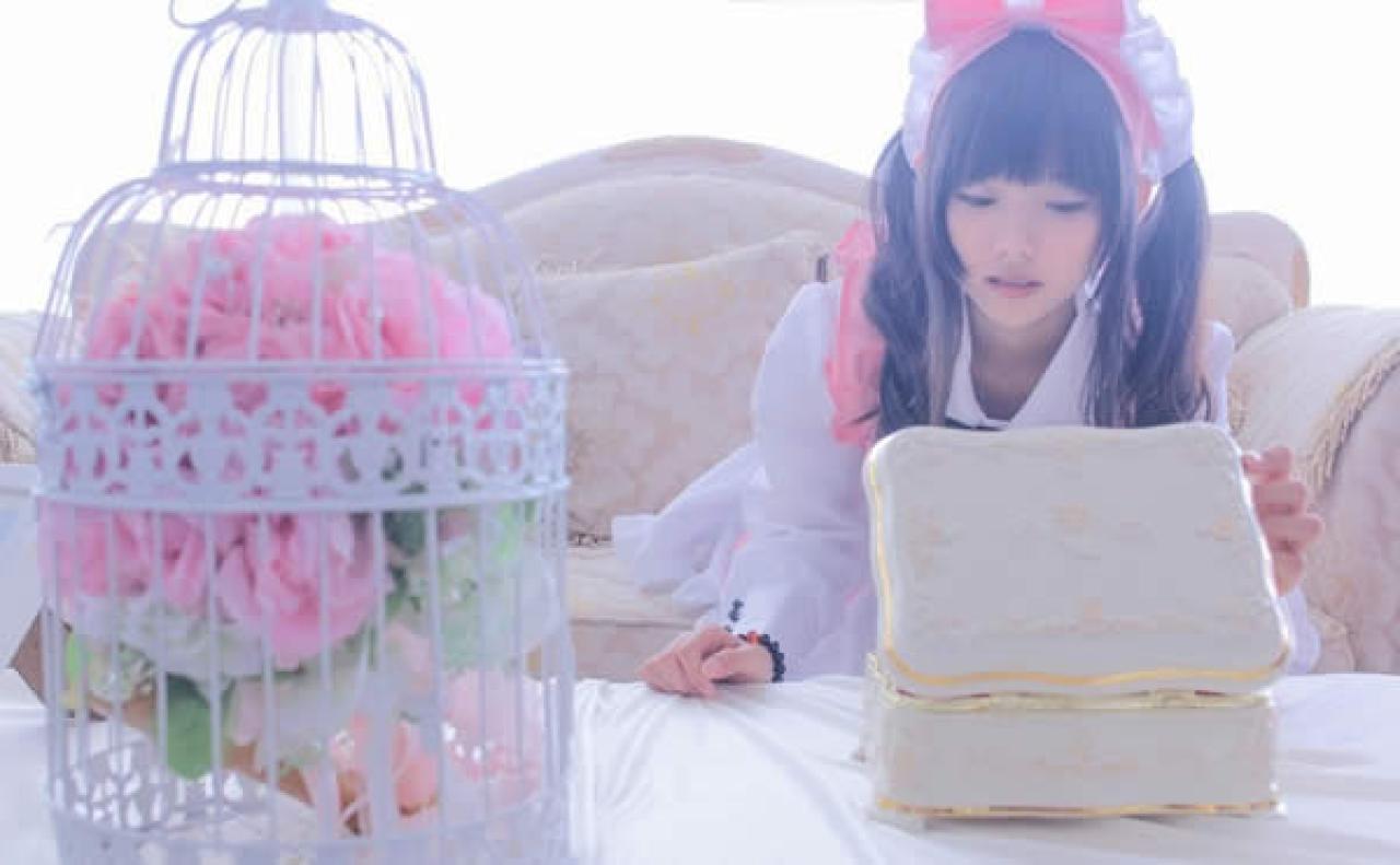 粉衣女仆装的猫梓坐在沙发打开小盒子的样子