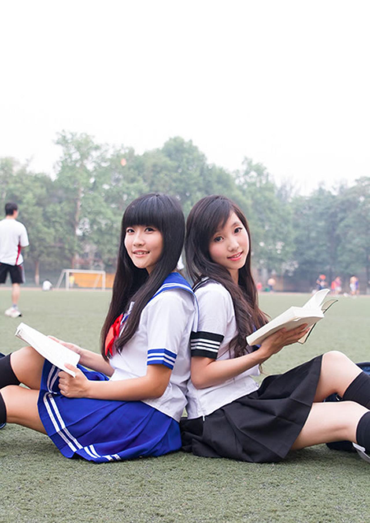 姊妹校服篇姐妹一起背靠背在操场看书的样子
