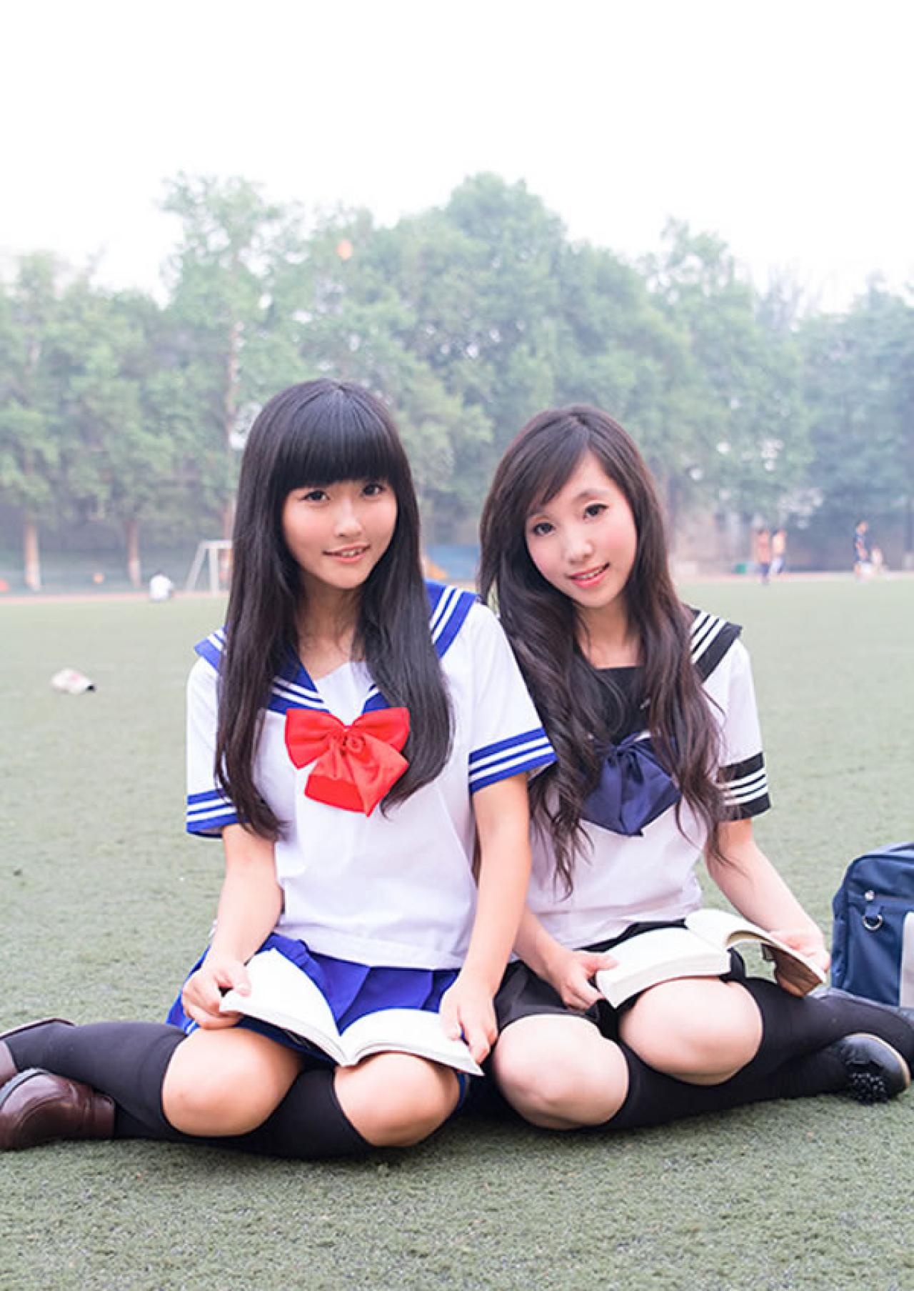 姊妹校服篇姐妹一起肩并肩在操场看书的样子