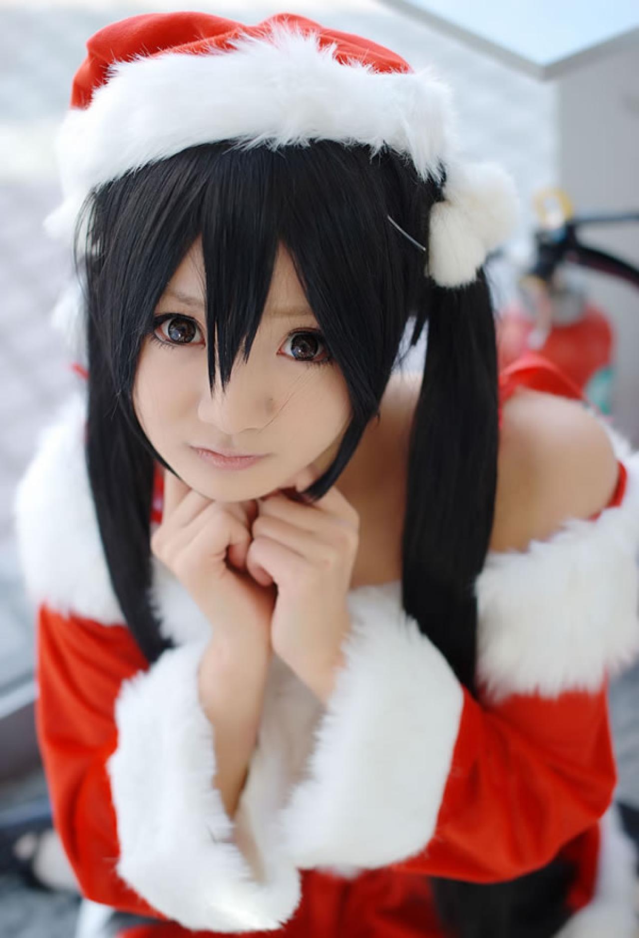 Maika Cos喵梓酱双手放在下巴，瞪大眼睛，作无辜思考状，特征为双马尾、圣诞服