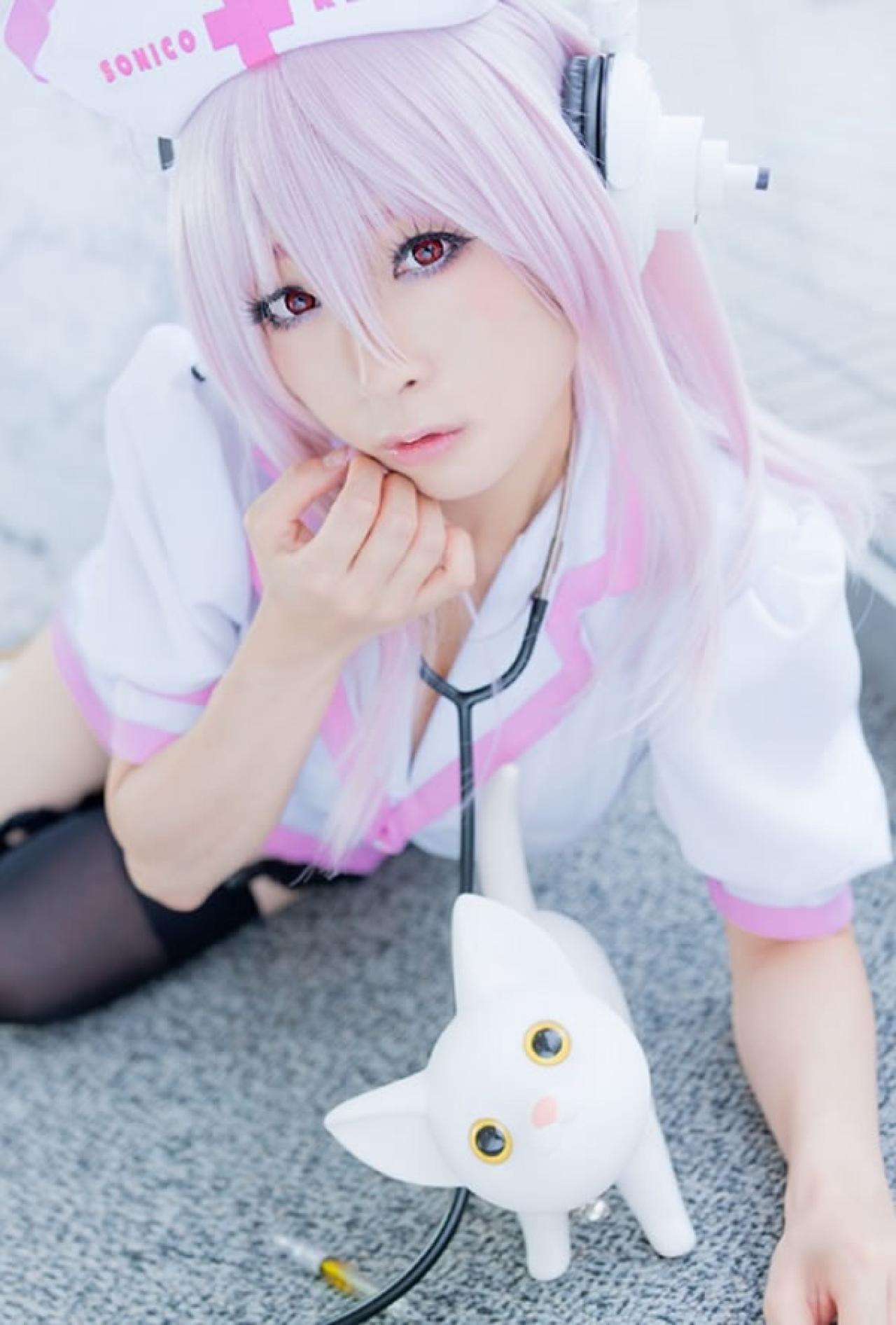 K@ori扮演超级索尼子身穿白色护士服趴在地上轻抚下巴的样子