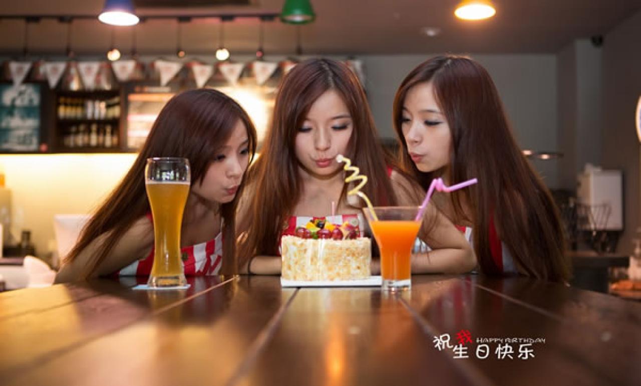 几位穿红色条纹衣裤的姑娘在酒吧生日聚会，姐妹们争着吹蜡烛
