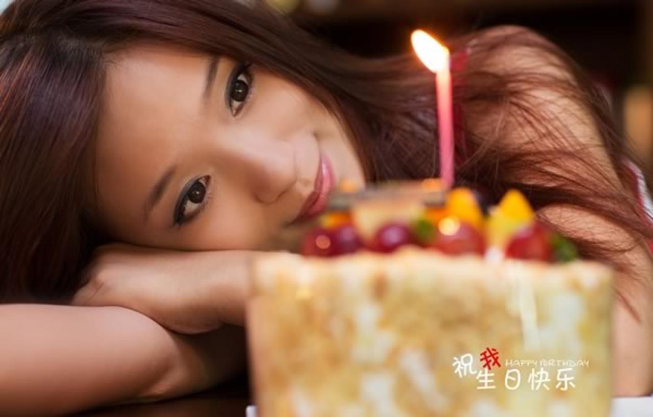 几位穿红色条纹衣裤的姑娘在酒吧生日聚会，过生日的姑娘趴在桌子上看着蜡烛