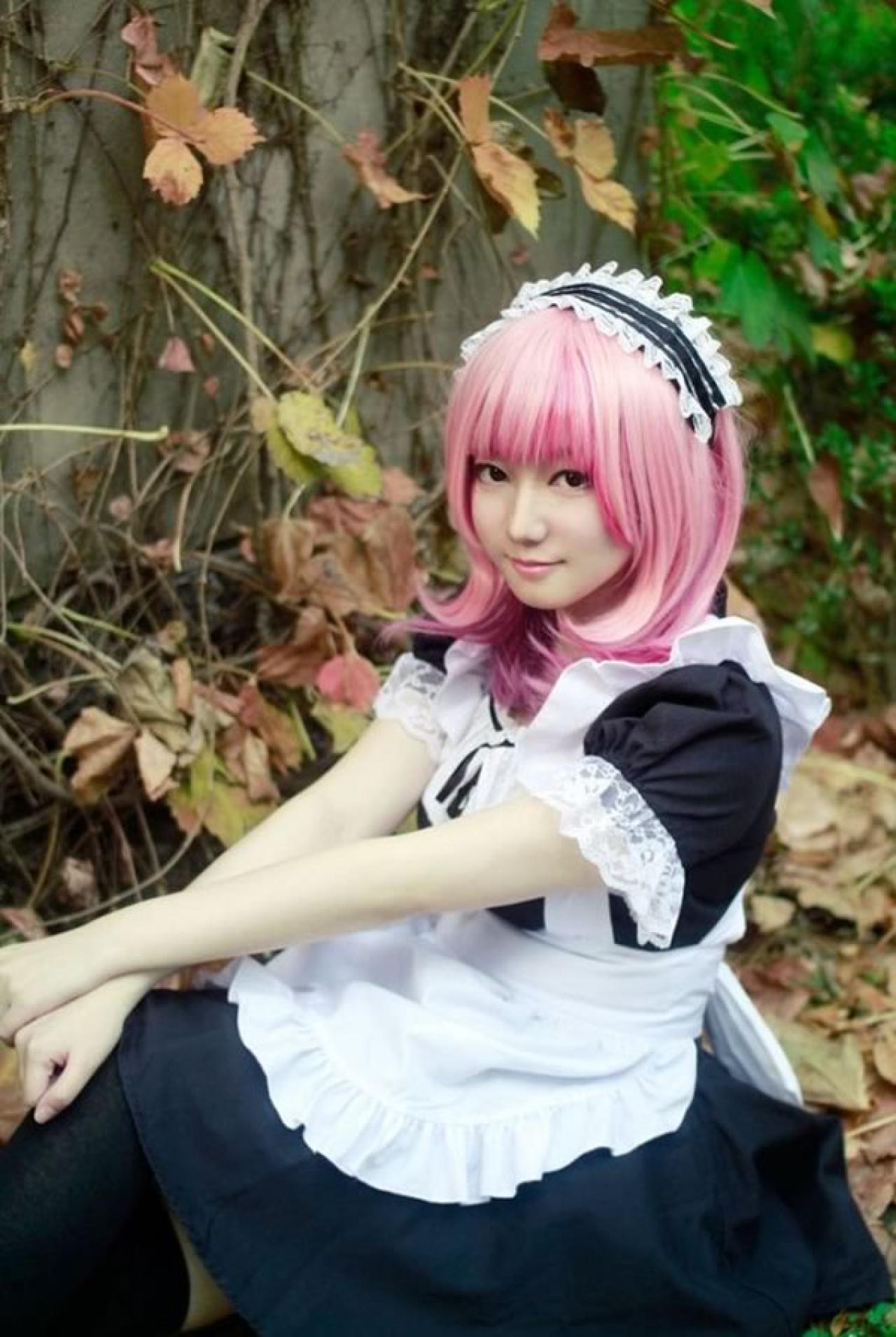 王雯雯Febii红发穿着黑色女仆装半坐在落叶铺满的地毯上，双手放在膝盖上，微笑的样子