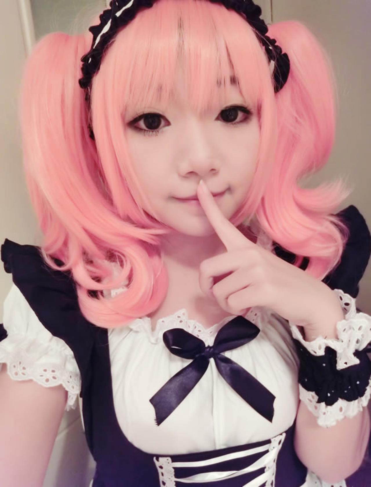 哀绿头戴粉色假发身穿黑色女仆装站姿，食指放在嘴唇前，作嘘的样子