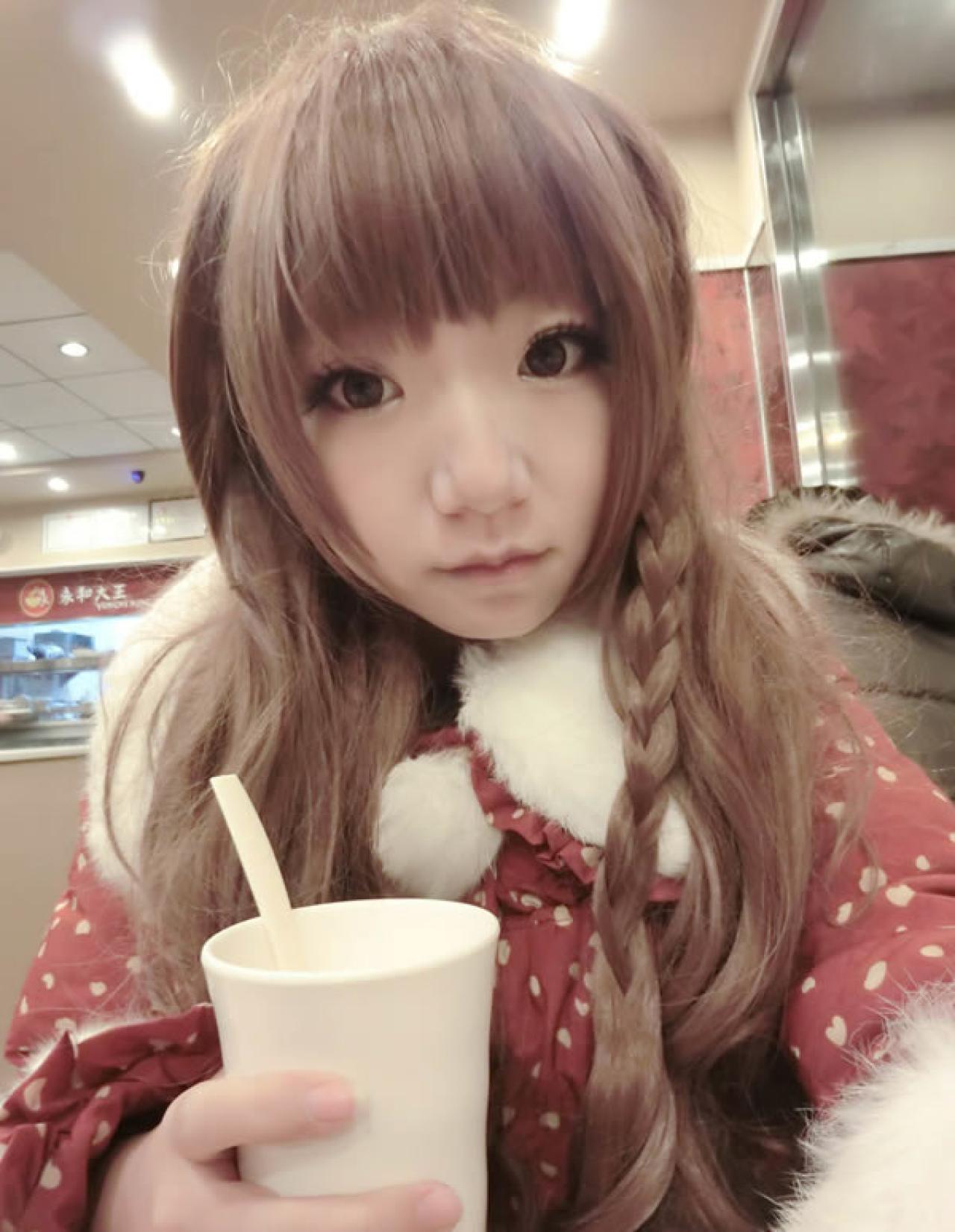 哀绿在13年12月24日平安夜晚在餐厅身穿红色桃心棉服的照片，咬紧嘴唇，手拿着饮料杯