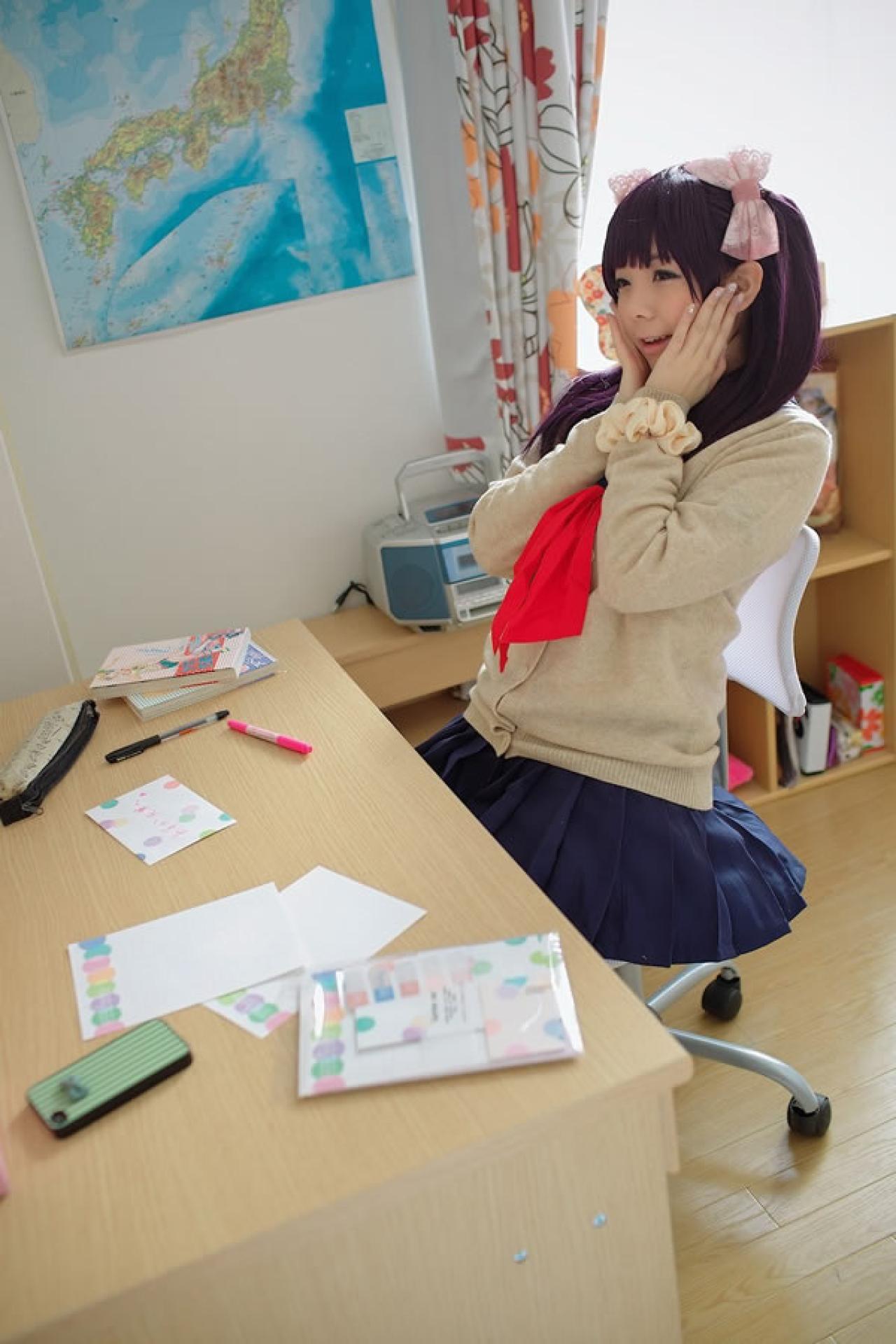 香坂ゆん扮演京野明日香身穿水手服和米色羊毛衫，双手捧着脸，靠在椅子上做惊喜的表情