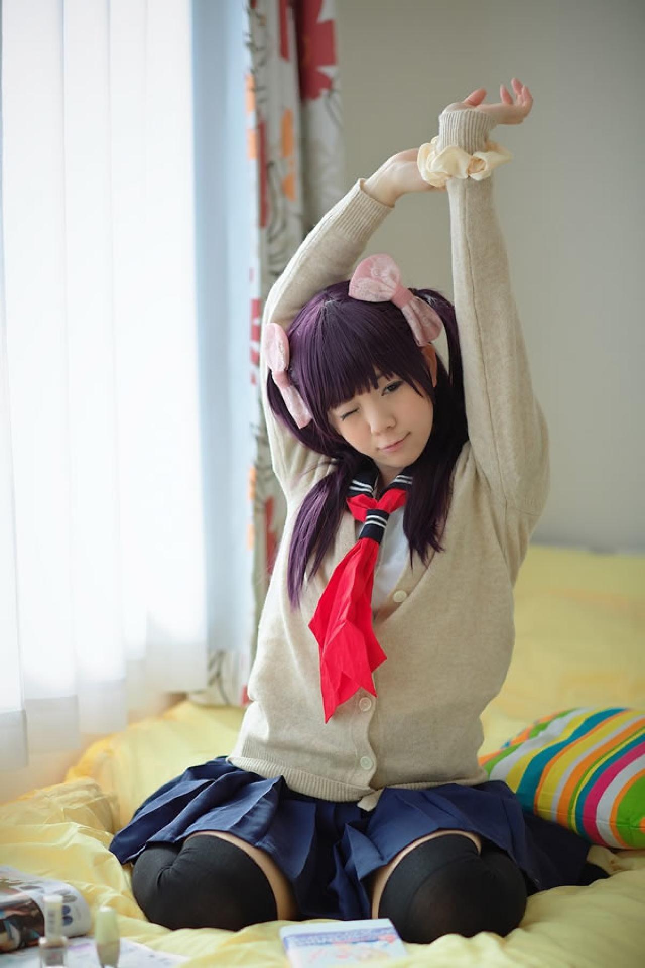 香坂ゆん扮演京野明日香身穿水手服和米色羊毛衫，坐在床上伸懒腰的样子，睁一只眼闭一只眼