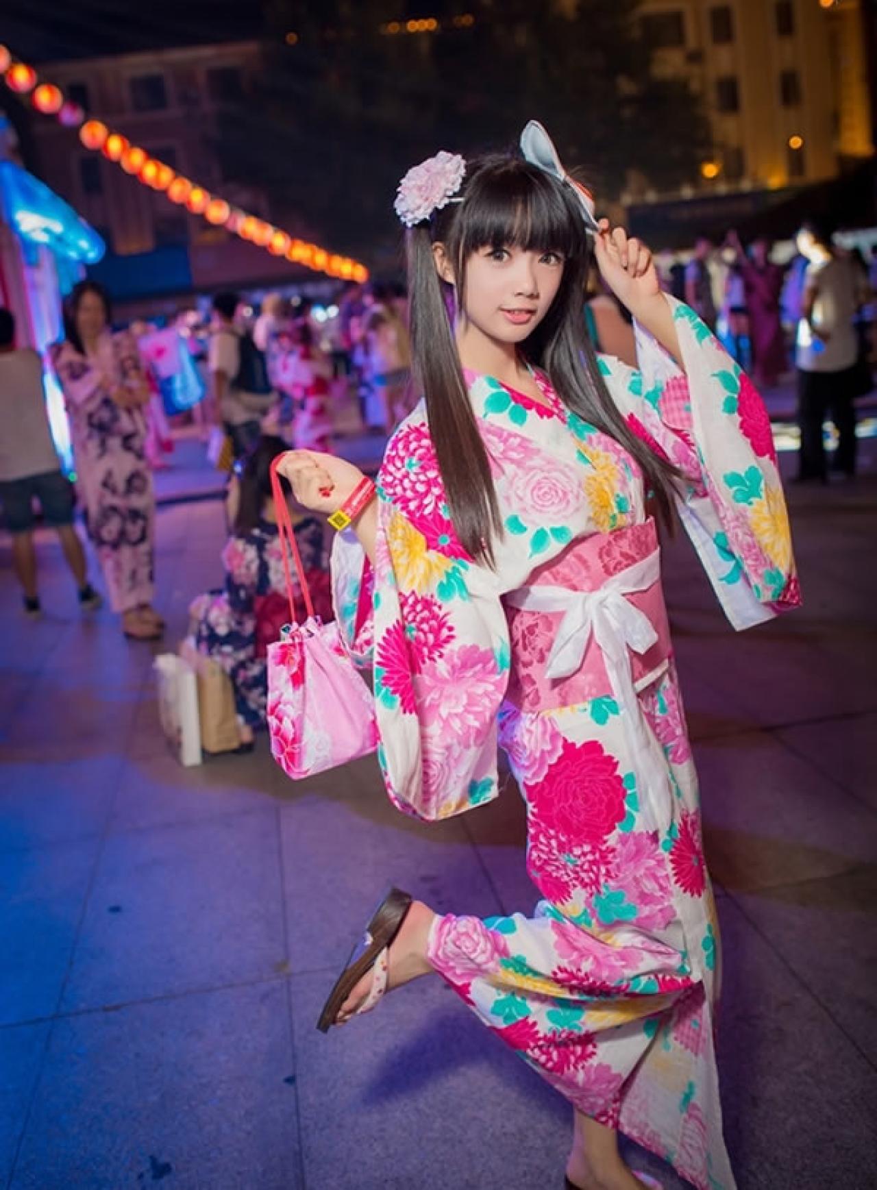 茶叶小果在卡弗动漫游戏展晚间夏日祭粉色和服浴衣街拍，左手捏着面具，右手拎着束口袋的，翘起腿的正面照