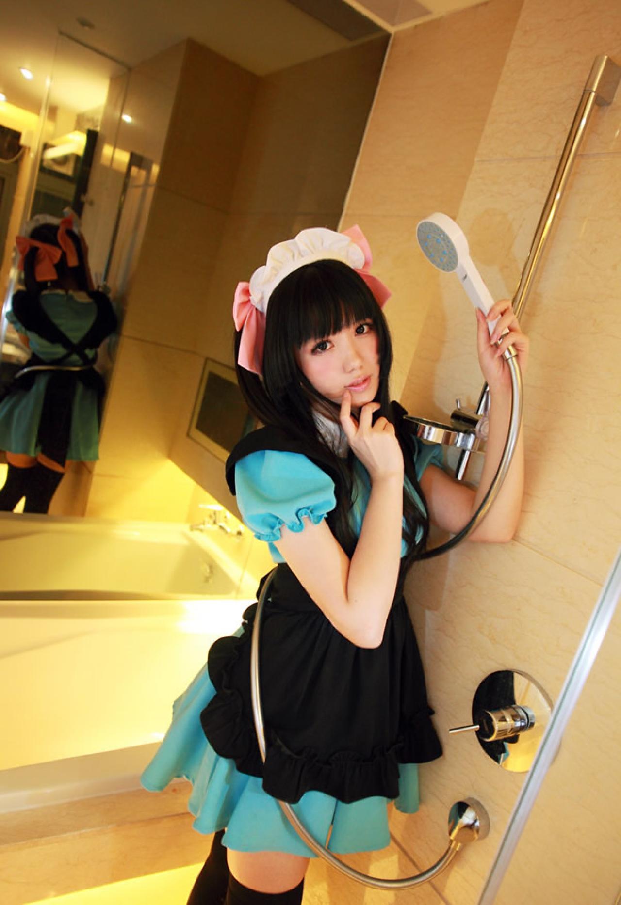 小米穿着绿色女仆装粉红发饰，举着淋浴喷头，依偎在墙壁上