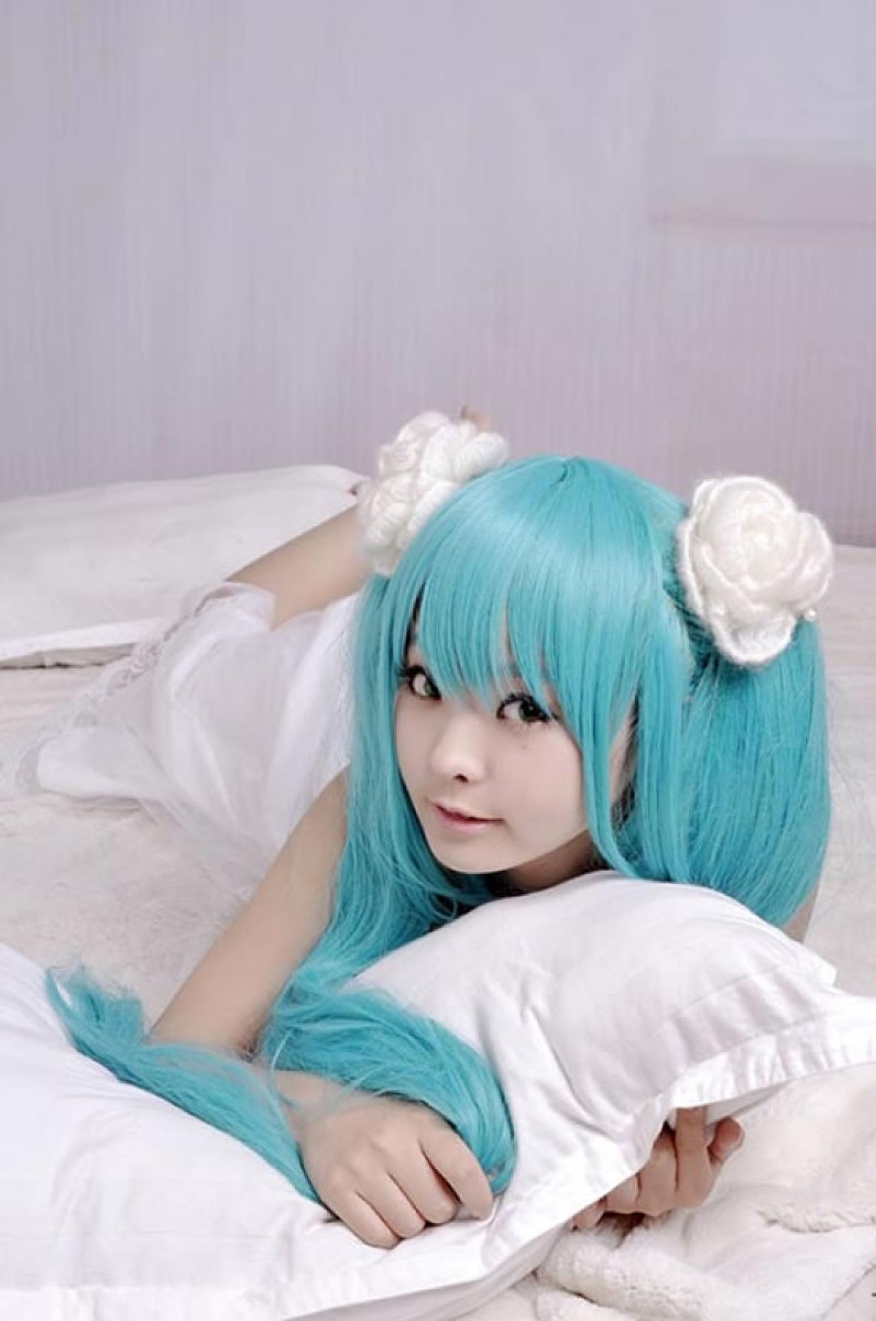 kuuya穿着白色睡衣扮演初音未来趴在床上抱着枕头的样子