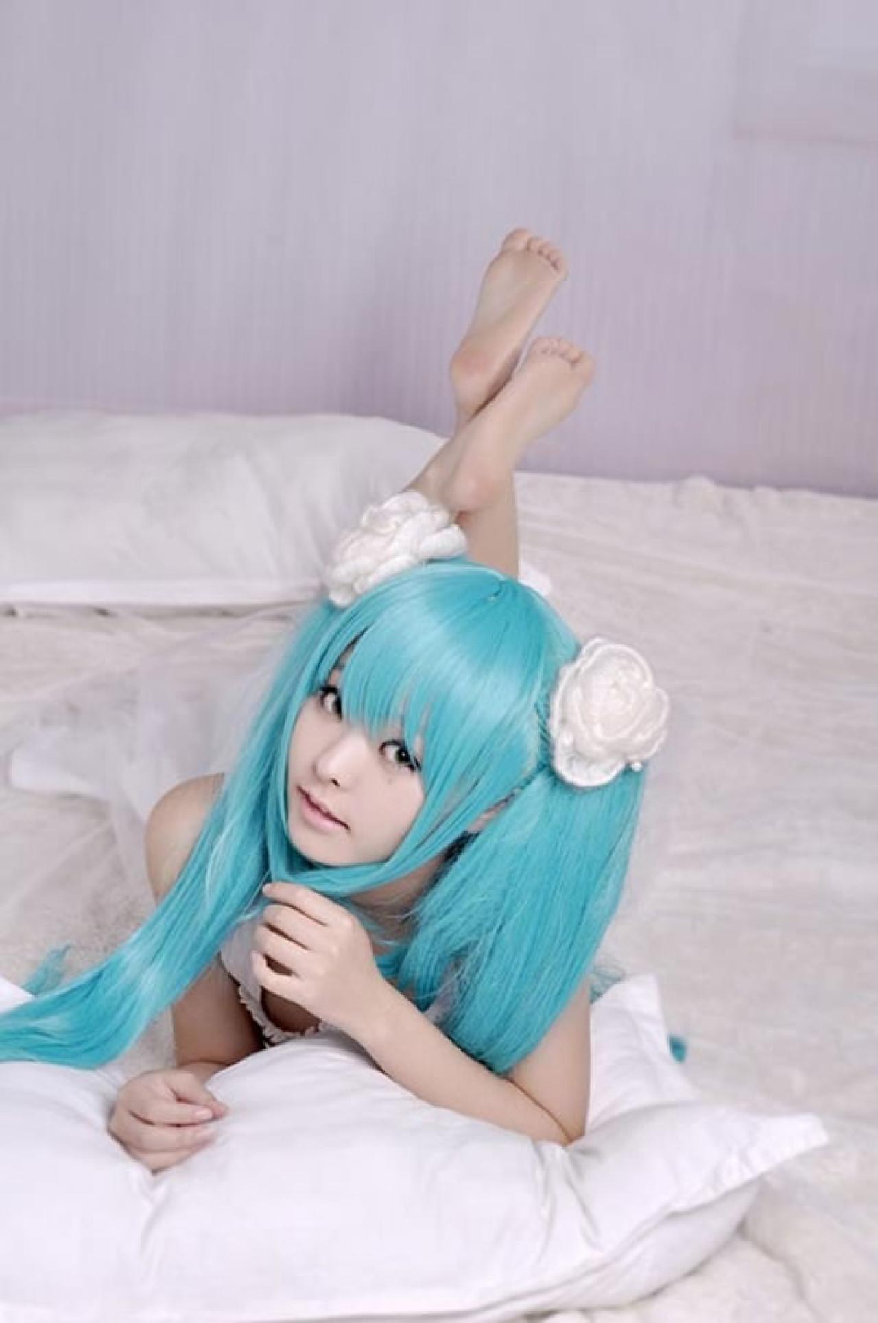 kuuya穿着白色睡衣扮演初音未来趴在枕头上，双腿翘起的调皮模样