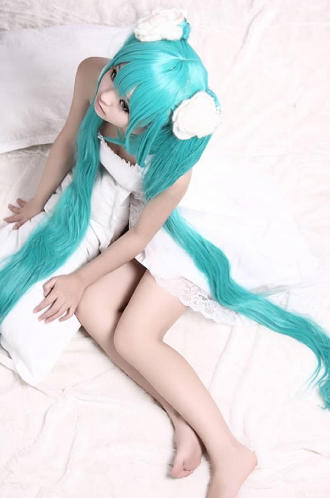 kuuya穿着白色睡衣扮演初音未来坐在枕头上，侧身俯拍