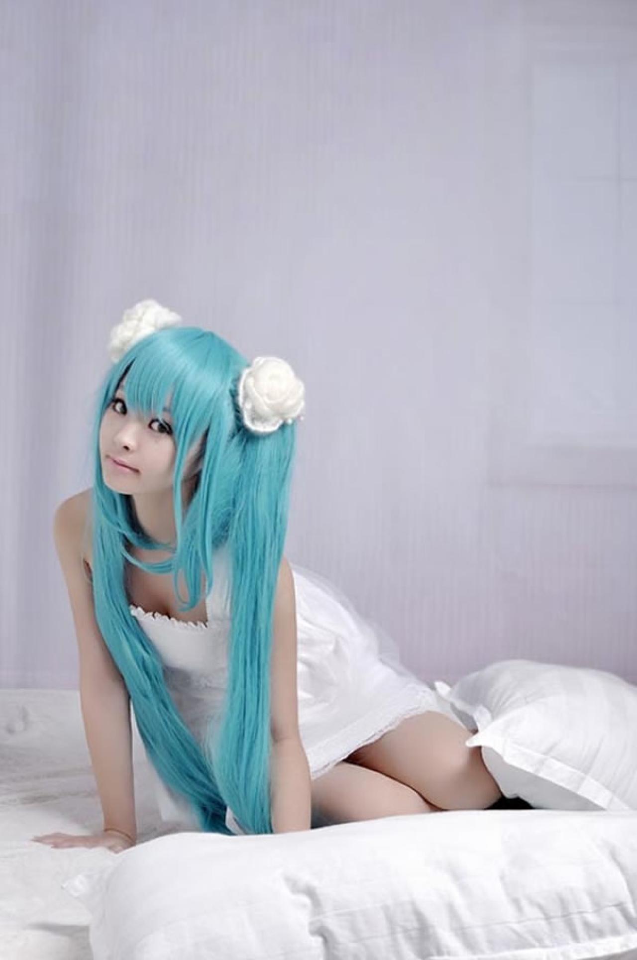 kuuya穿着白色睡衣扮演初音未来半跪在床上，双手扶在床面的样子