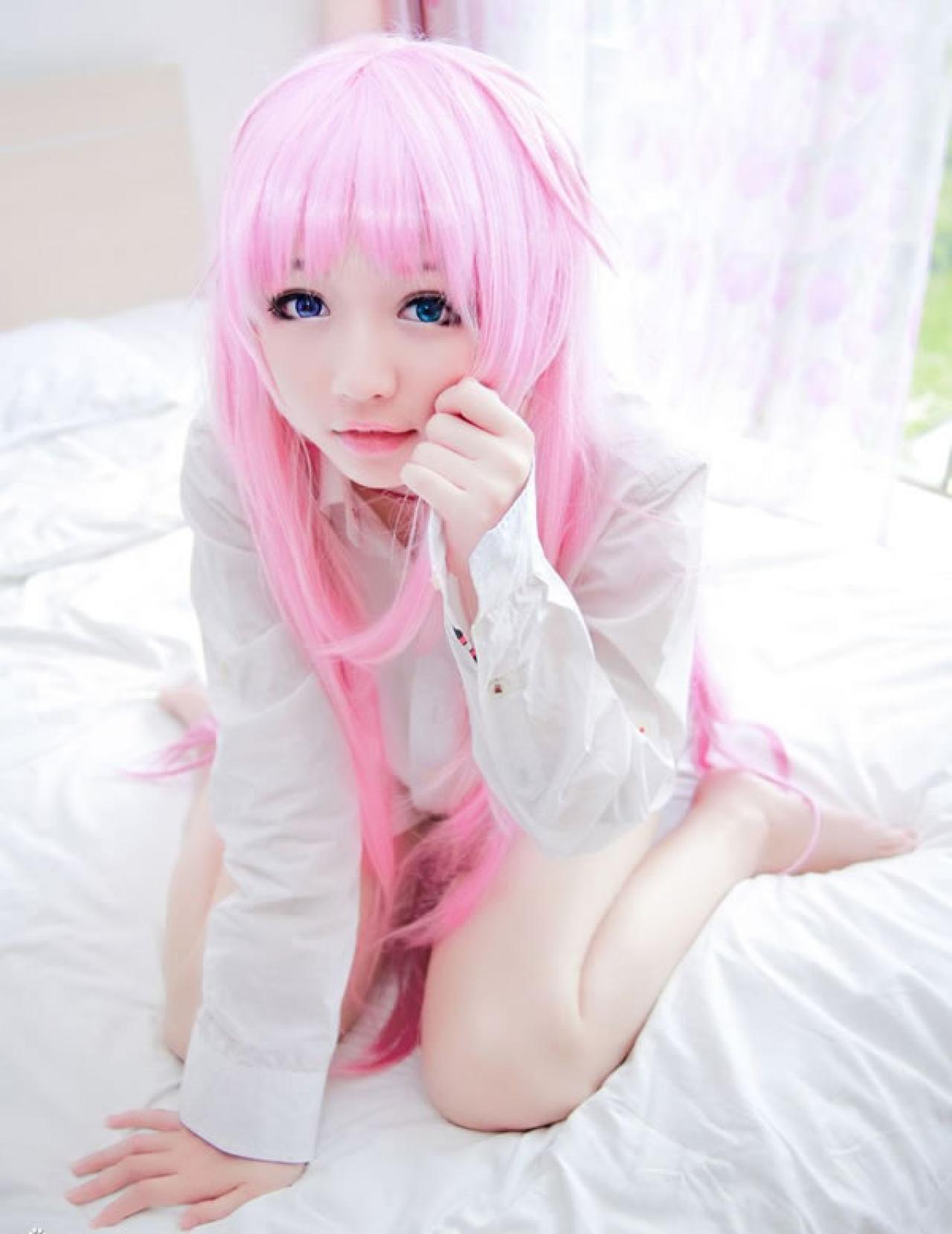 摆摆扮演《K》粉色猫娘，半跪在床上，用手抚摸脸的样子