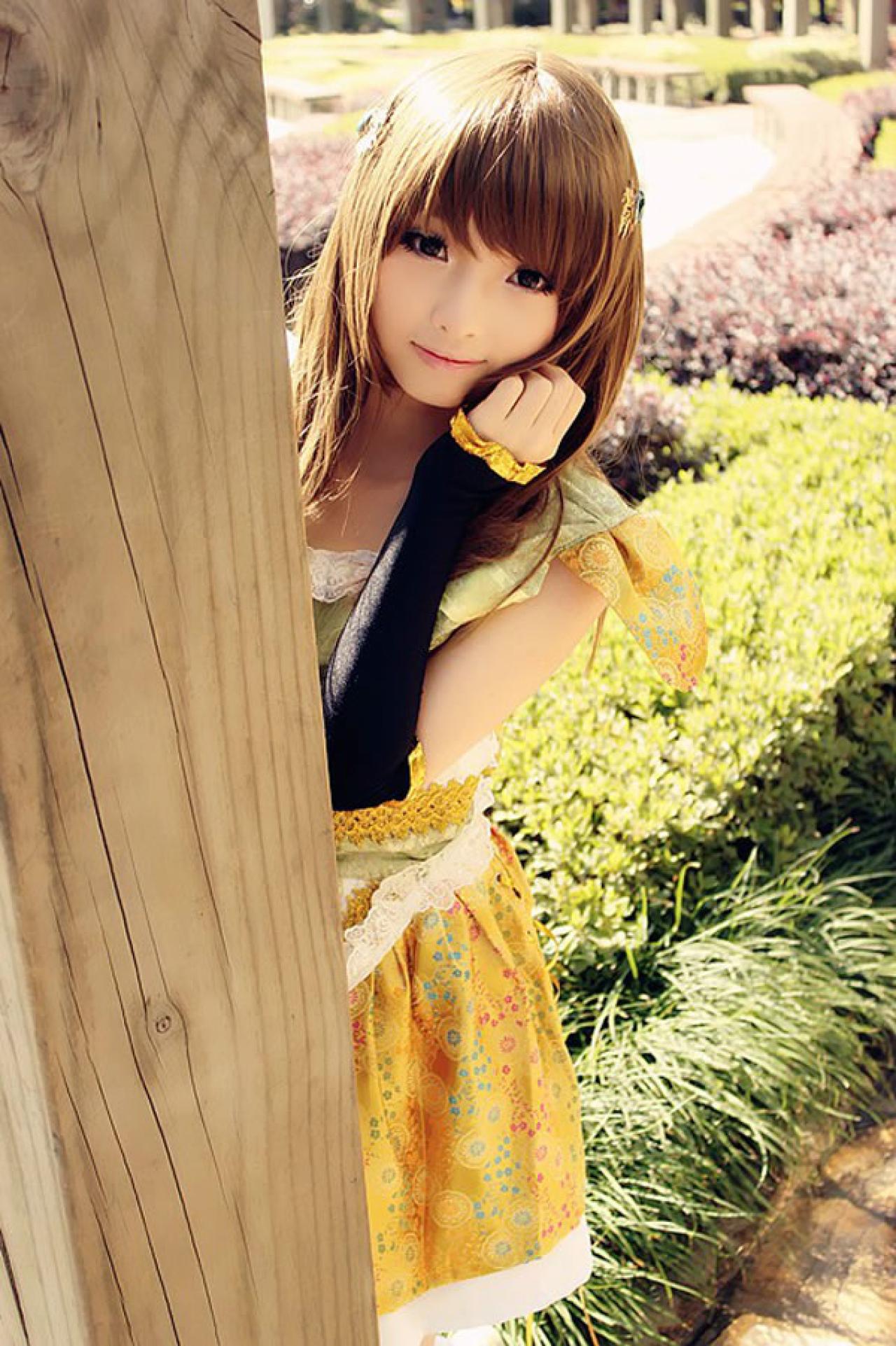 CC喵穿着黄色古装扮演小乔藏着木头后面，探出头看着镜头