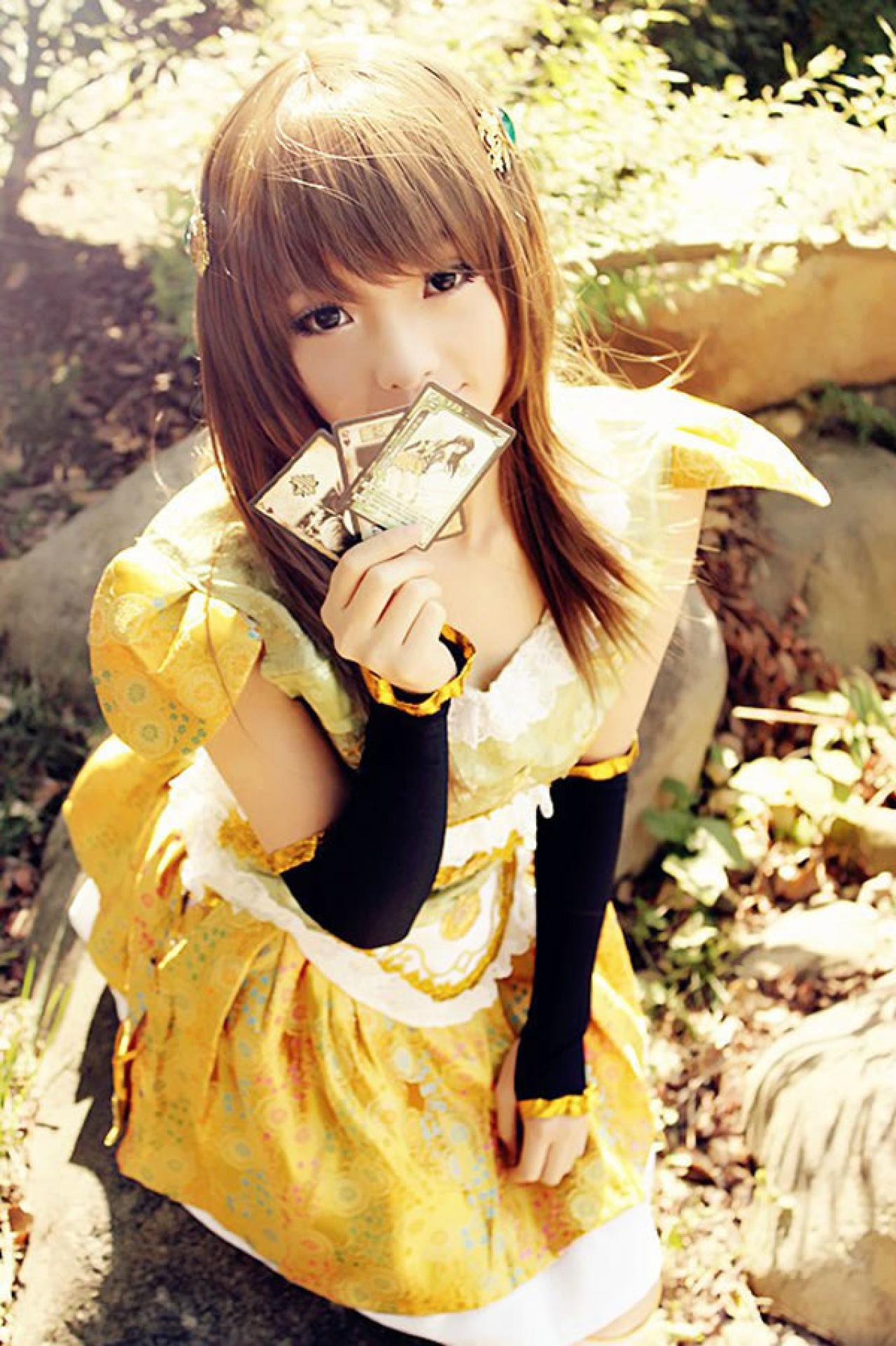 CC喵穿着黄色古装扮演小乔半跪在铺满落叶的地上，亲吻着三张三国杀卡牌