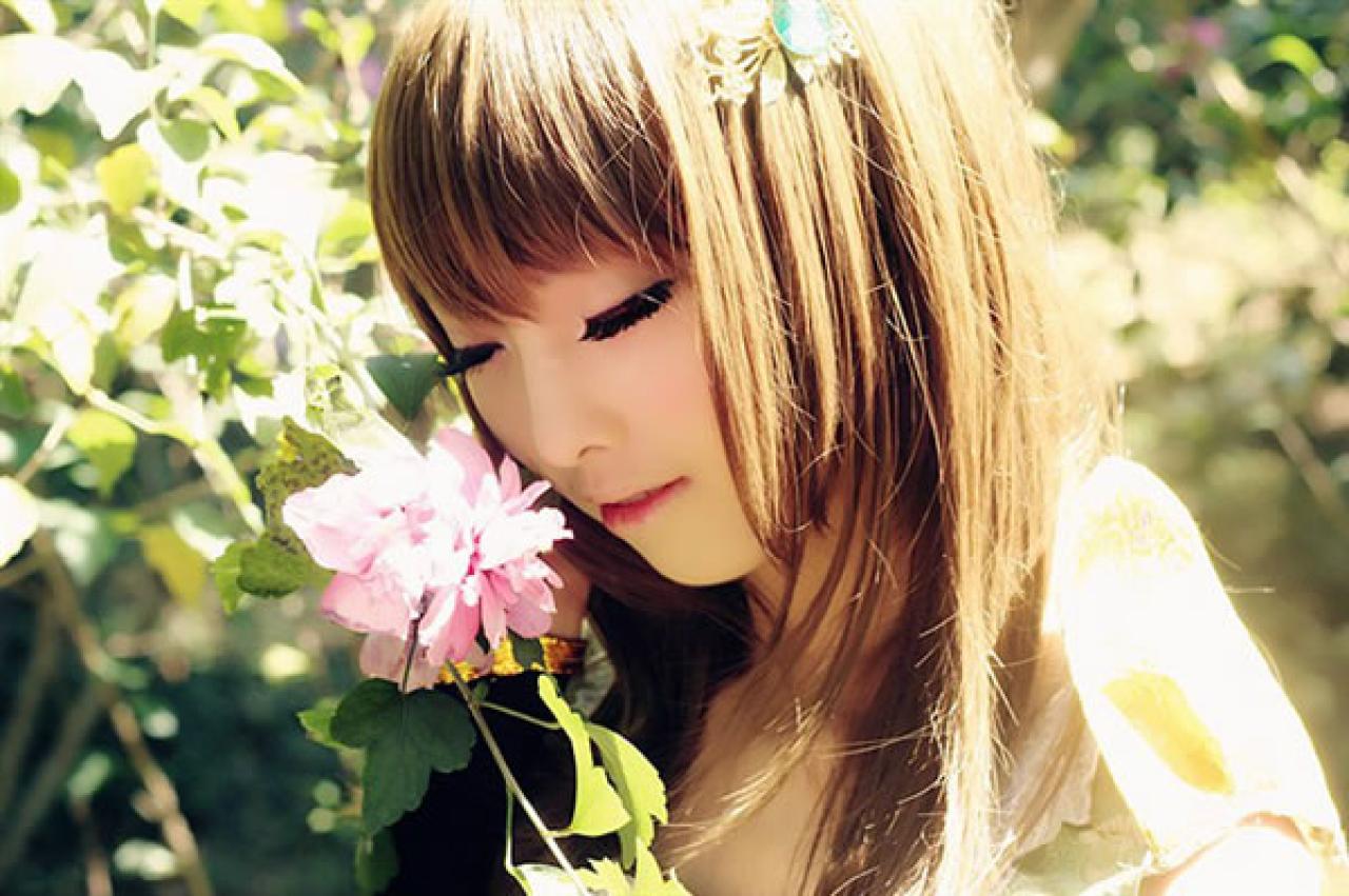 CC喵穿着黄色古装扮演小乔低头轻轻闻着一朵粉色鲜花，陶醉的样子