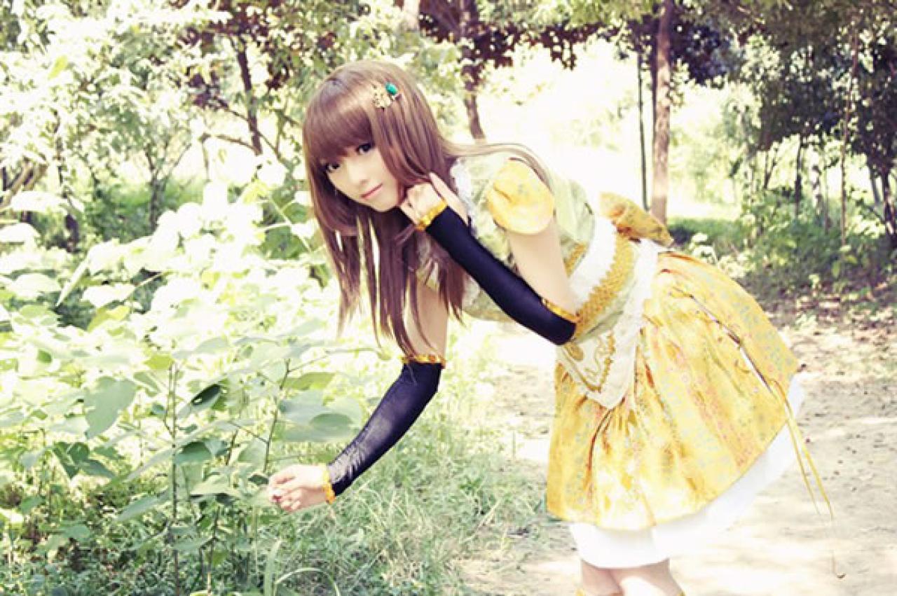 CC喵穿着黄色古装扮演小乔俯身轻轻捏着一片叶子的侧面