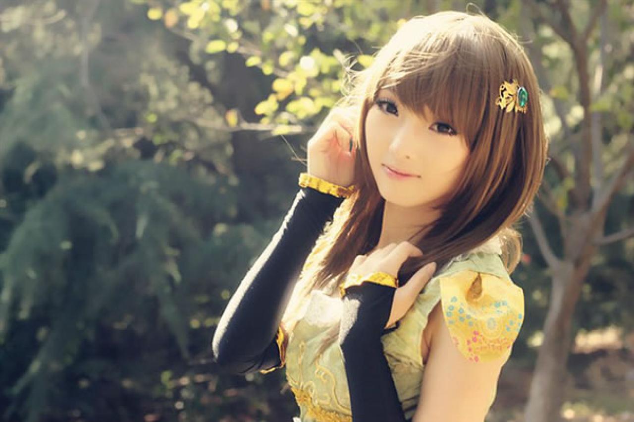 CC喵穿着黄色古装扮演小乔双手抚摸棕色头发的上半身侧面