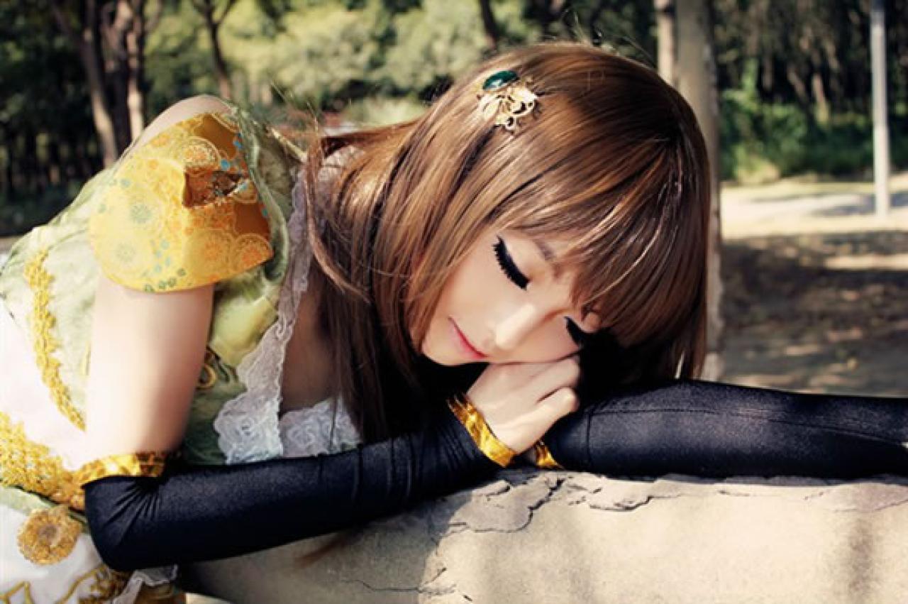 CC喵穿着黄色古装扮演小乔侧身伸展手臂，扒在树木长椅上