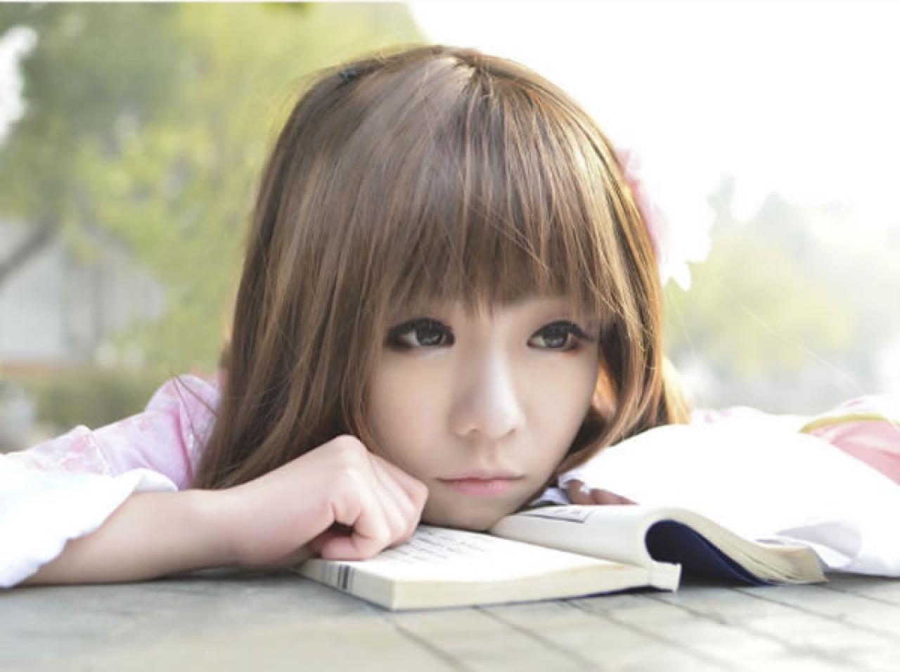 季_凋葬穿着粉衣扮演湾娘扒在书本，睁开大眼睛，略有所思的看着前方