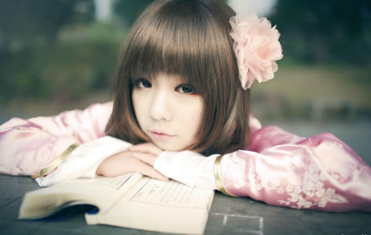 季_凋葬穿着粉衣扮演湾娘趴在石桌上，大眼睛眨巴眨巴卖萌的横幅照片