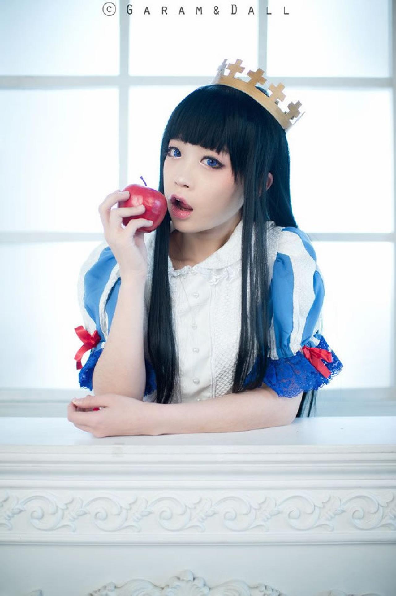 兔娘Tomia穿着蓝白洋装扮演白雪公主扶在桌子上张开嘴想要吃苹果的样子