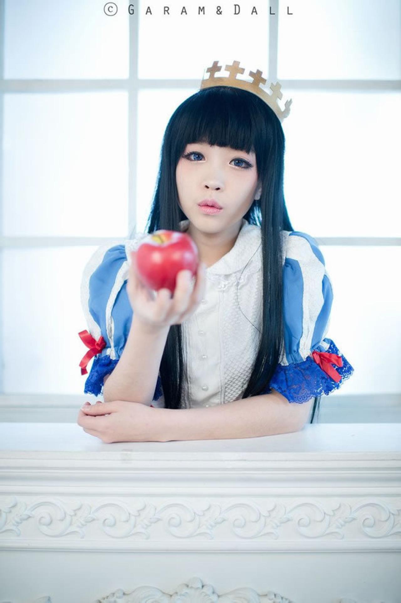 兔娘Tomia穿着蓝白洋装扮演白雪公主嘟着嘴，伸手拿苹果给镜头前