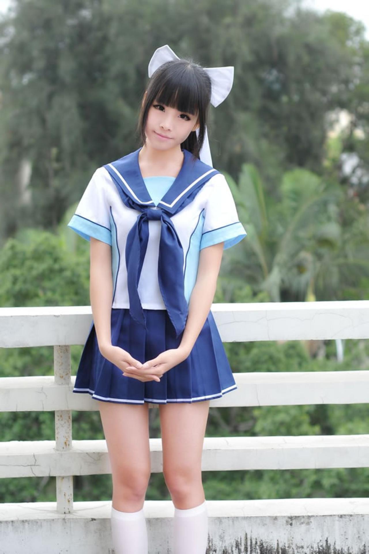 熊酱穿着蓝色学院校服扮演高岭爱花，双手手指拉在一起，自然下摆靠在天台栏杆站立的姿势