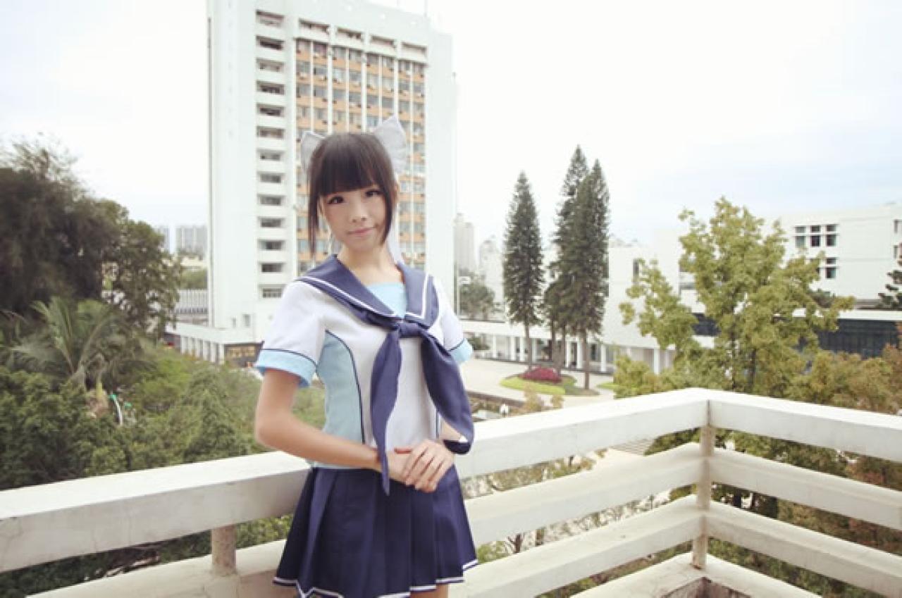 熊酱穿着蓝色学院校服扮演高岭爱花，双手叠放在一起放在腰间，靠在窗台栏杆上的侧面照