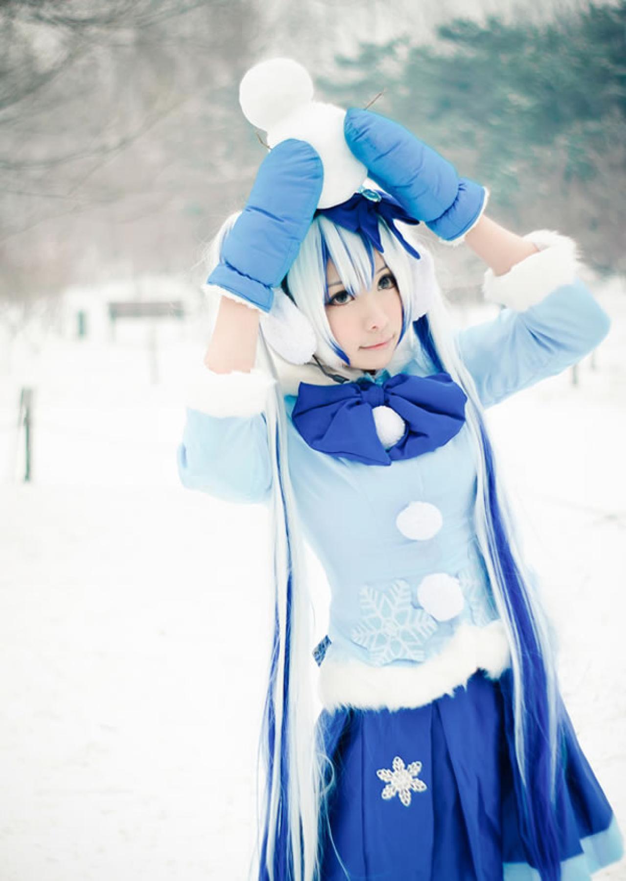 贤儿sherry穿着蓝色棉服扮演雪初音，在白雪皑皑中将一个小雪人顶在头上