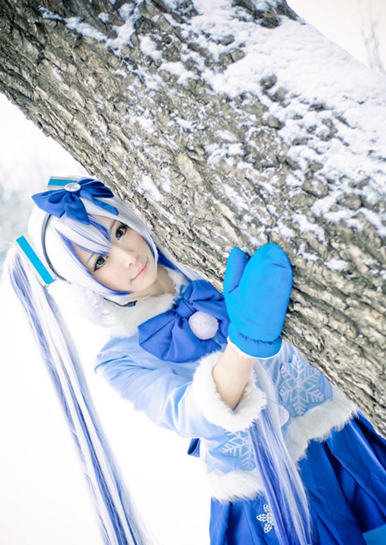 贤儿sherry穿着蓝色棉服扮演雪初音，藏在树后，抱着树干