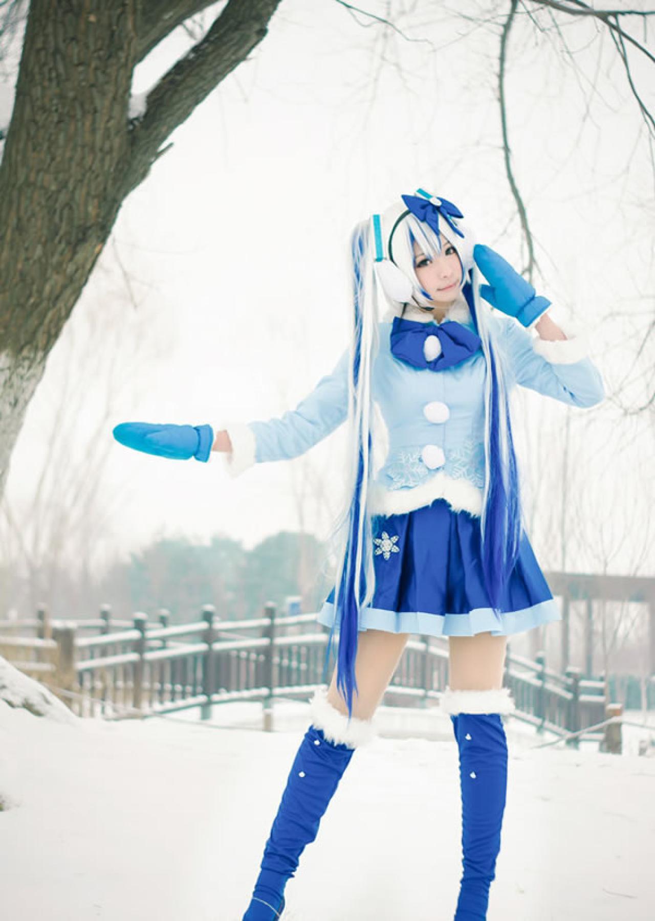 贤儿sherry穿着蓝色棉服扮演雪初音，正在树旁，双手摇向树干