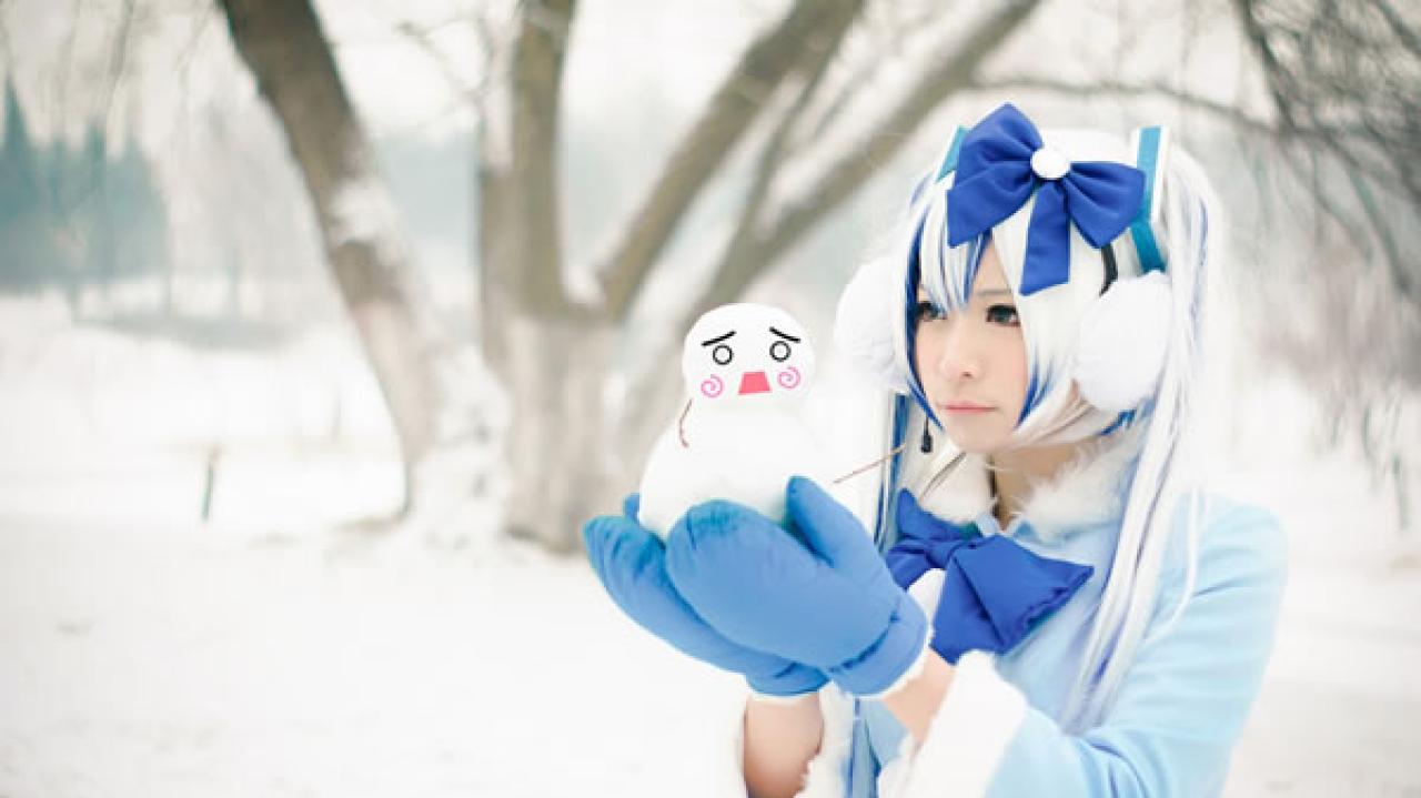 贤儿sherry穿着蓝色棉服扮演雪初音，轻轻在手里捧着一个小雪人