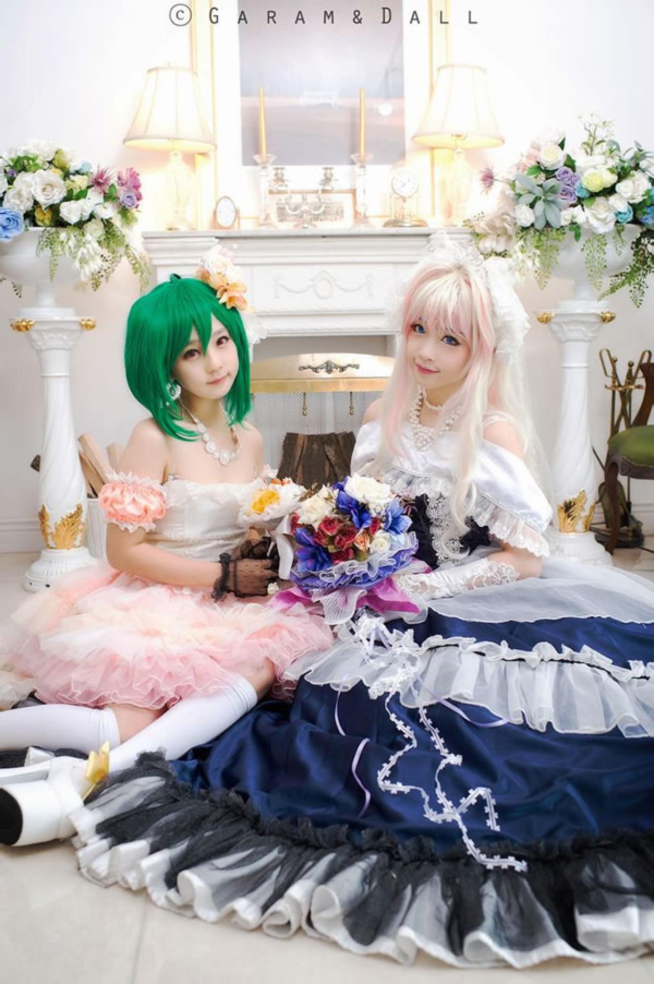 雪露·诺姆穿着蓝色洋装和兰歌·李穿着粉色洋装双手捧着鲜花坐在洋房里