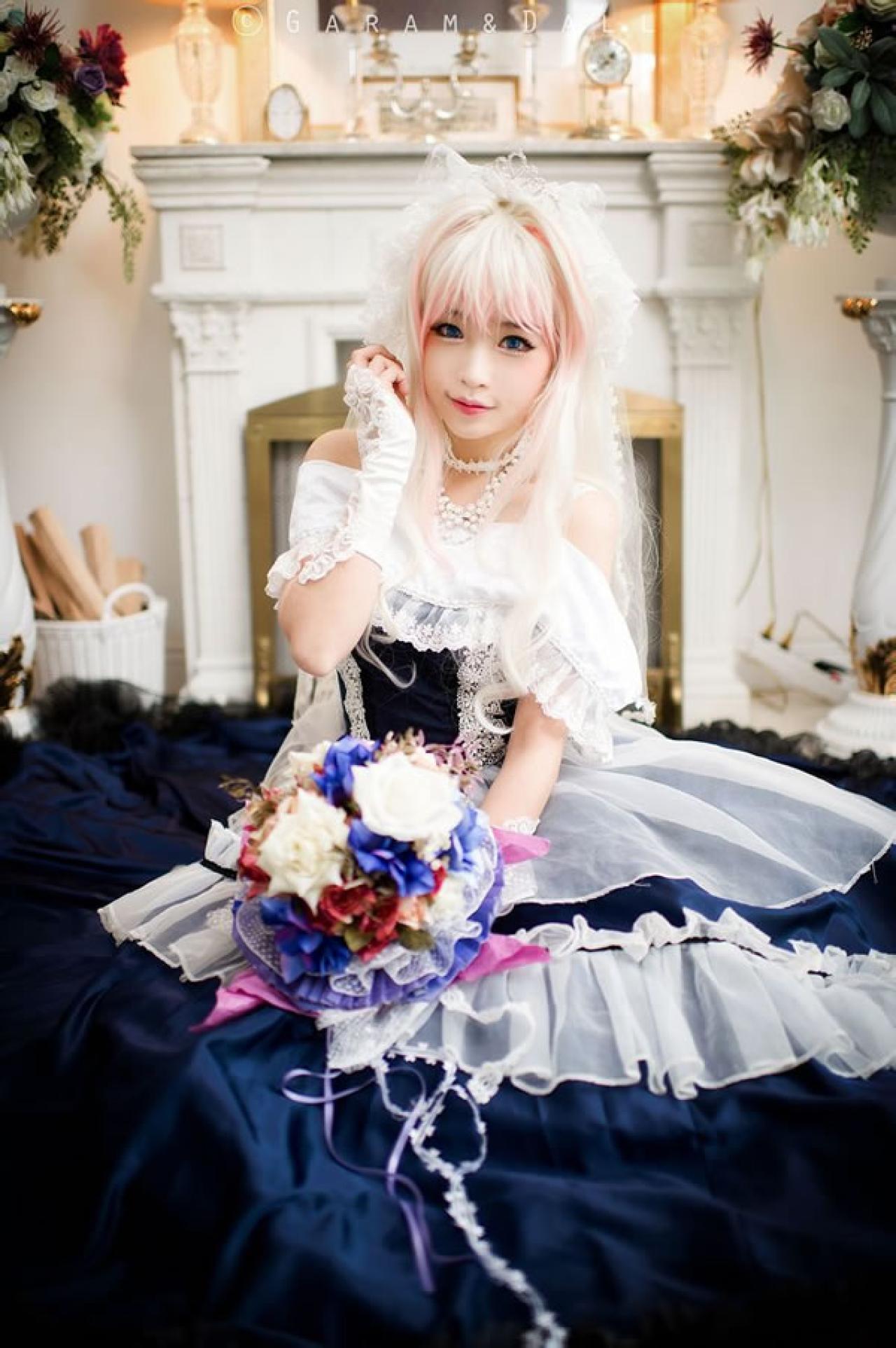 雪露·诺姆穿着蓝色洋装长裙铺展在地面，手捧鲜花正面