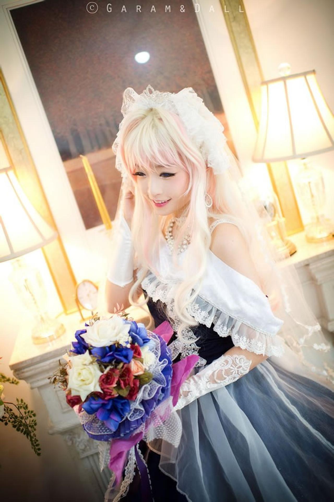 雪露·诺姆穿着蓝色洋装在台灯旁颔首微笑的样子