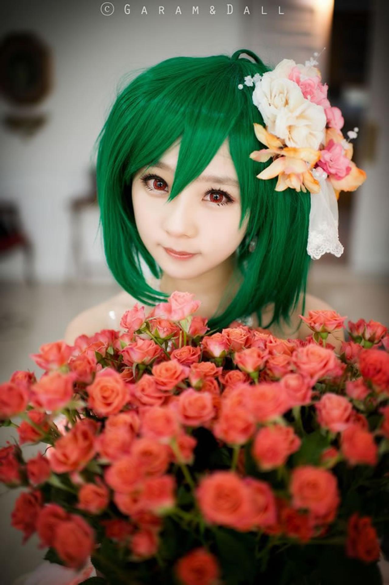 穿着粉色洋装的兰歌·李站在一大束红色玫瑰花后