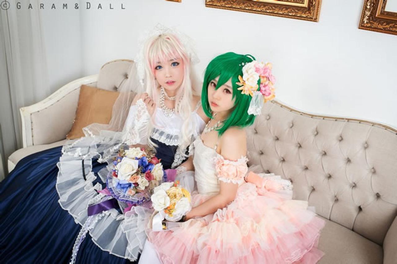 雪露·诺姆穿着蓝色洋装提着裙摆站在穿着粉色洋装的兰歌·李都捧着鲜花在沙发依靠而做