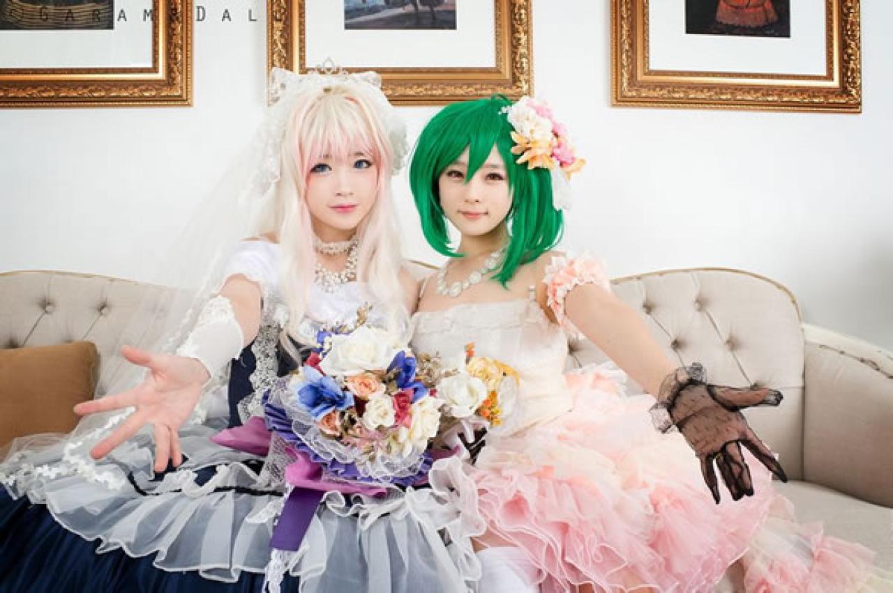 雪露·诺姆穿着蓝色洋装提着裙摆站在穿着粉色洋装的兰歌·李双方各伸出一只手