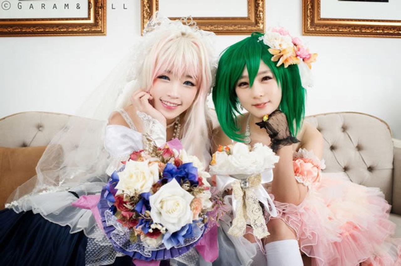 雪露·诺姆穿着蓝色洋装提着裙摆站在穿着粉色洋装的兰歌·李双方都捧着脸微笑