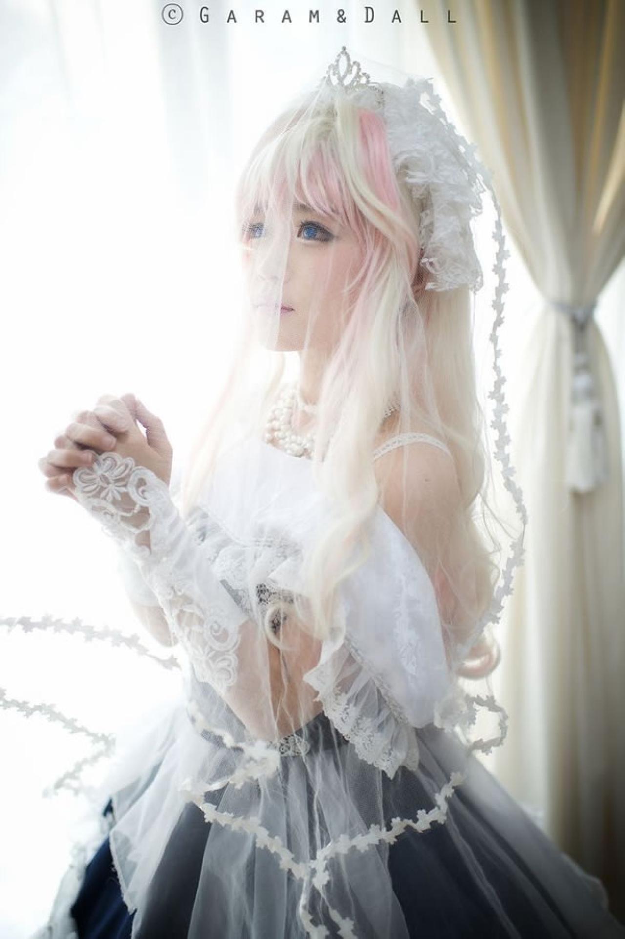 雪露·诺姆穿着蓝色洋装披着白色纱巾，双手握在一起，祈祷的样子