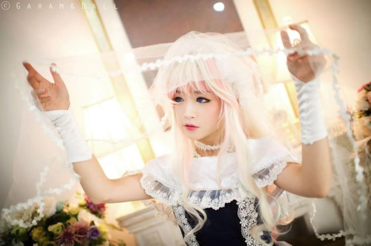 雪露·诺姆穿着蓝色洋装双手撑起纱巾，双眼撇向远处的样子