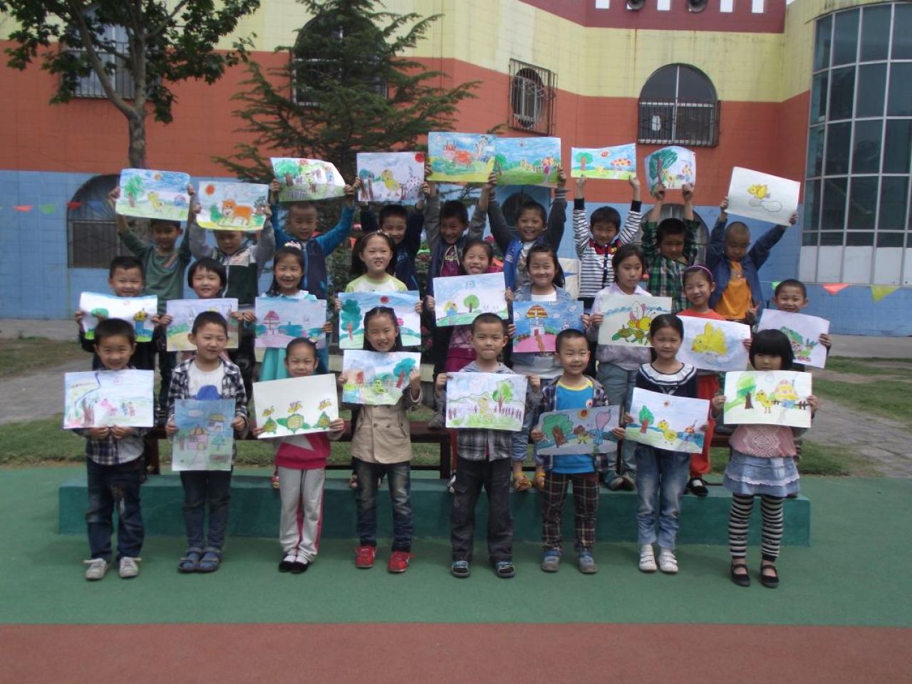 初小班的孩子们和他们的蜡笔画作品合影