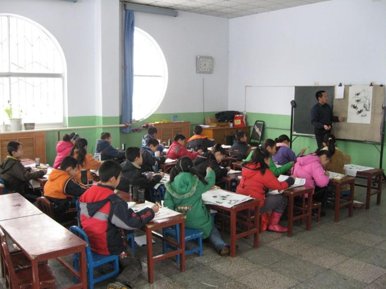 老师将毡子夹到黑板上，在黑板上演示国画中螃蟹的画法。