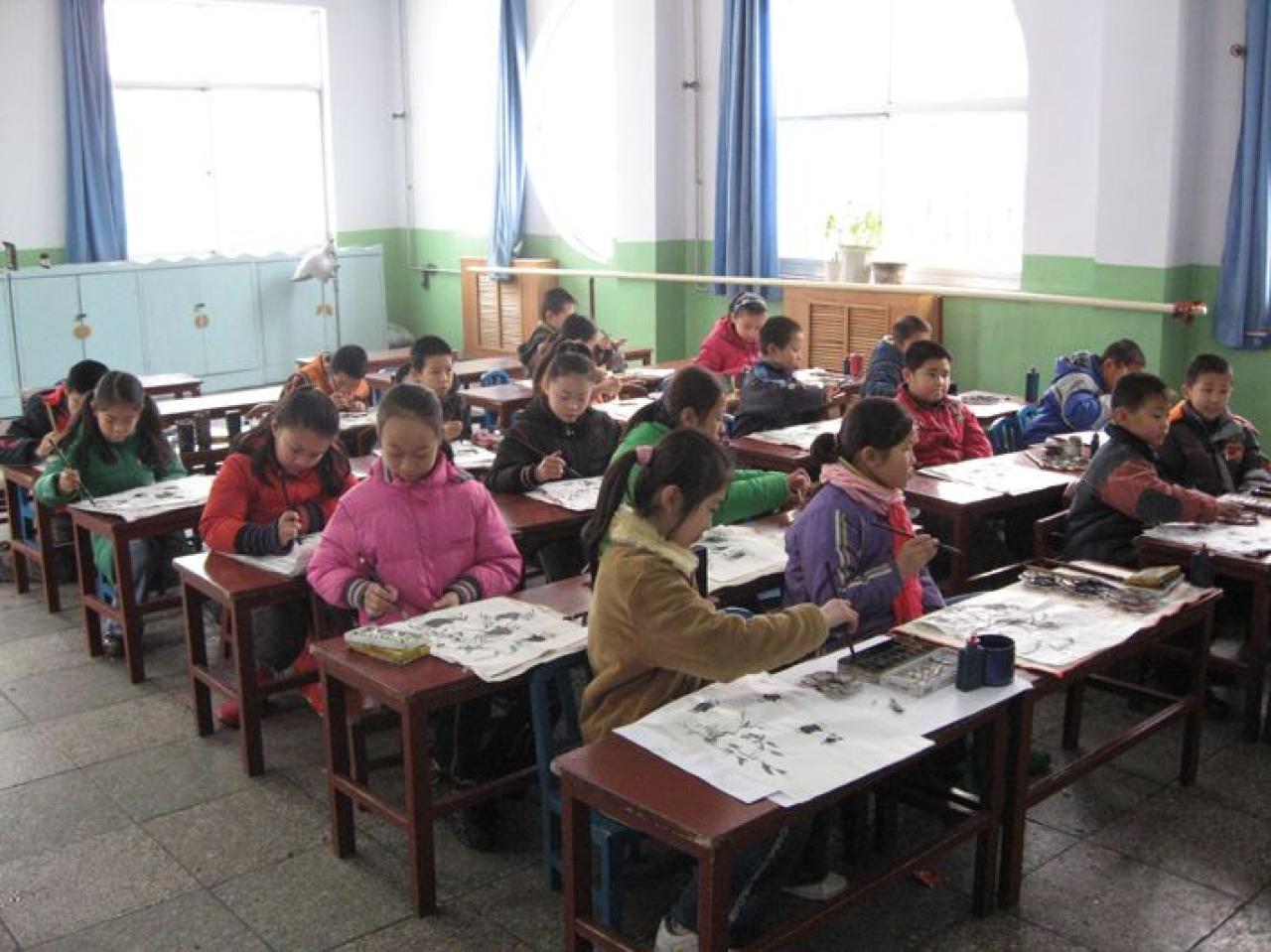 同学们正在边听老师讲，边按照黑板上的步骤绘制螃蟹。