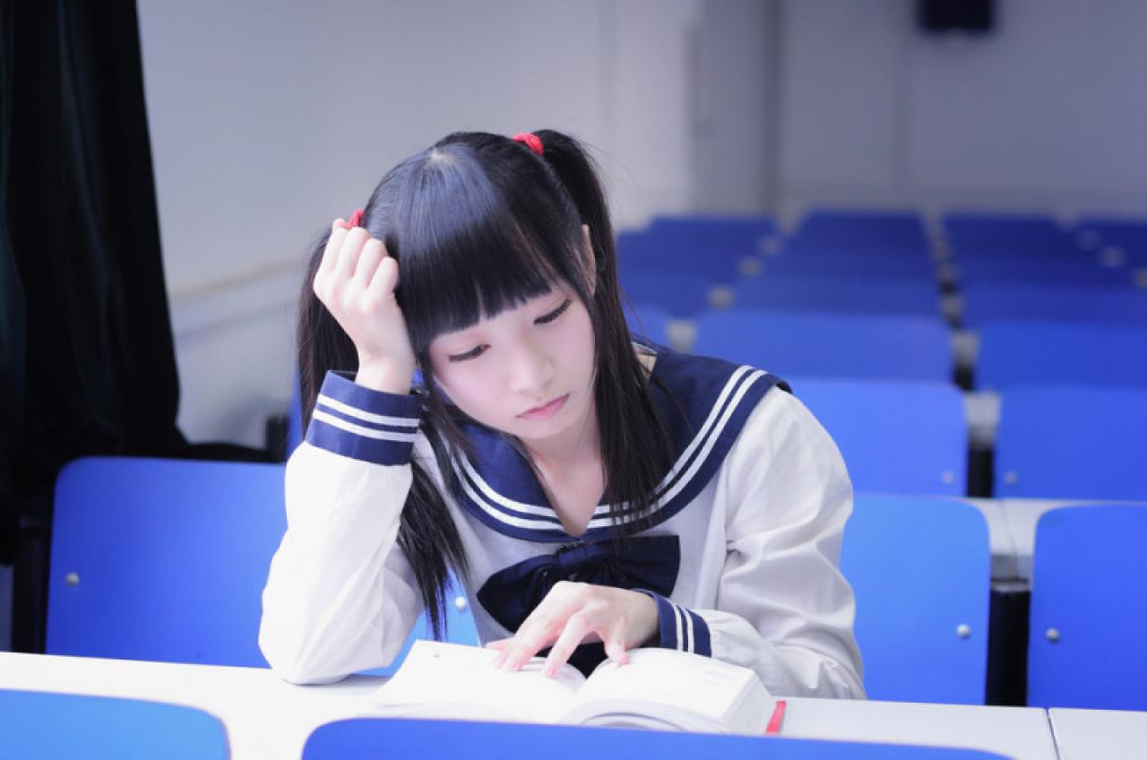 双马尾水手服少女右手抵着头，看书有点累了的样子