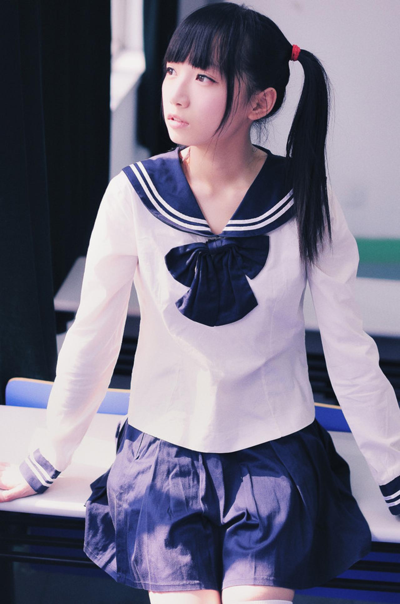 双马尾水手服少女双手支坐在课桌上，眼睛斜向窗外