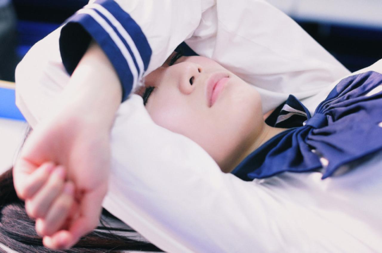 双马尾水手服少女躺在课桌上，闭上眼睛享受窗外的阳光